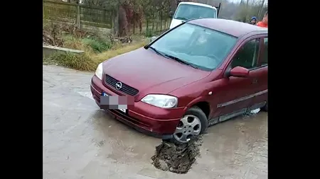 Drum reabilitat recent, plin de GROPI – O mașină a rămas blocată într-un crater imens
